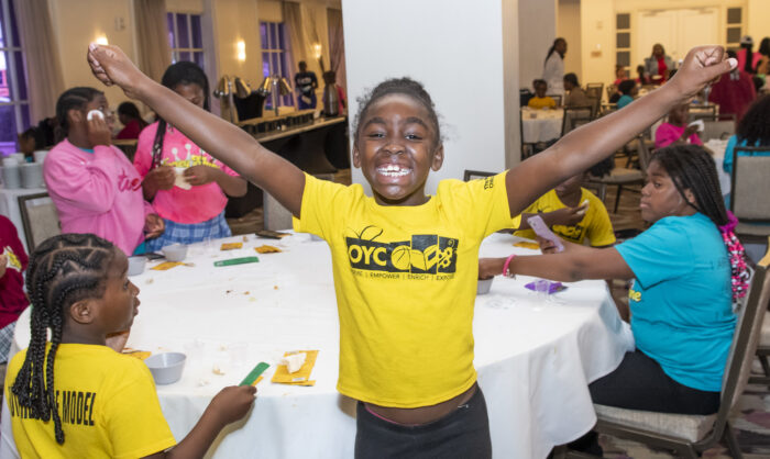 a young girl smile and raises her arms at the Honey Shine Spa Day