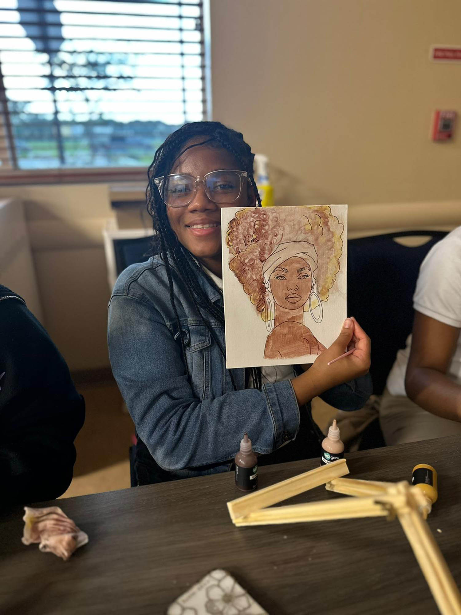 a young lady displays a painting she just completed