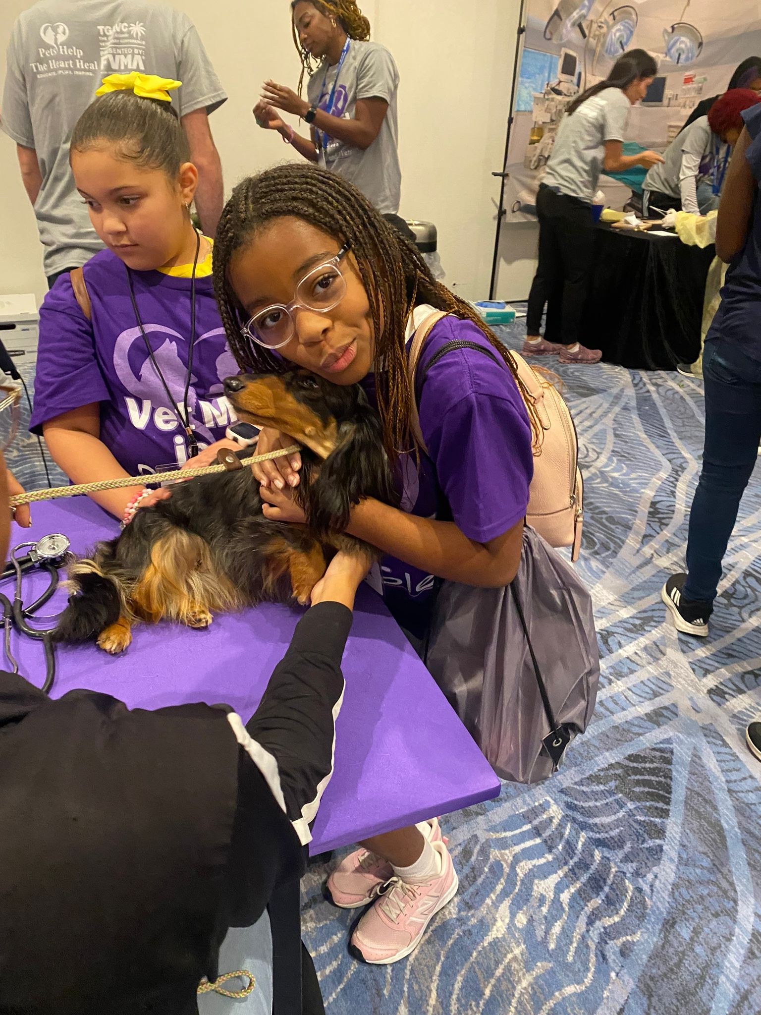 a young girl comforts a small dog on a veterinarian table