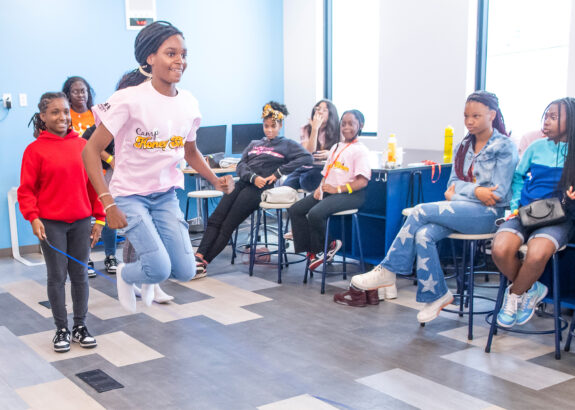 young girls participate in double-dutch jump roping inside a large room
